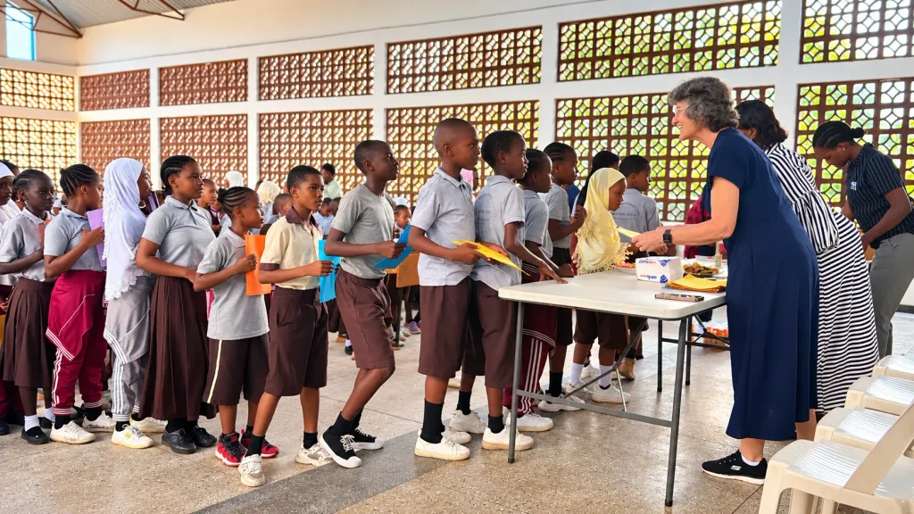 Students at Lawrence Academy line up to give Heidi birthday cards during a celebration at the school in Tanzania. Heidi smiles as she receives a card from a student.